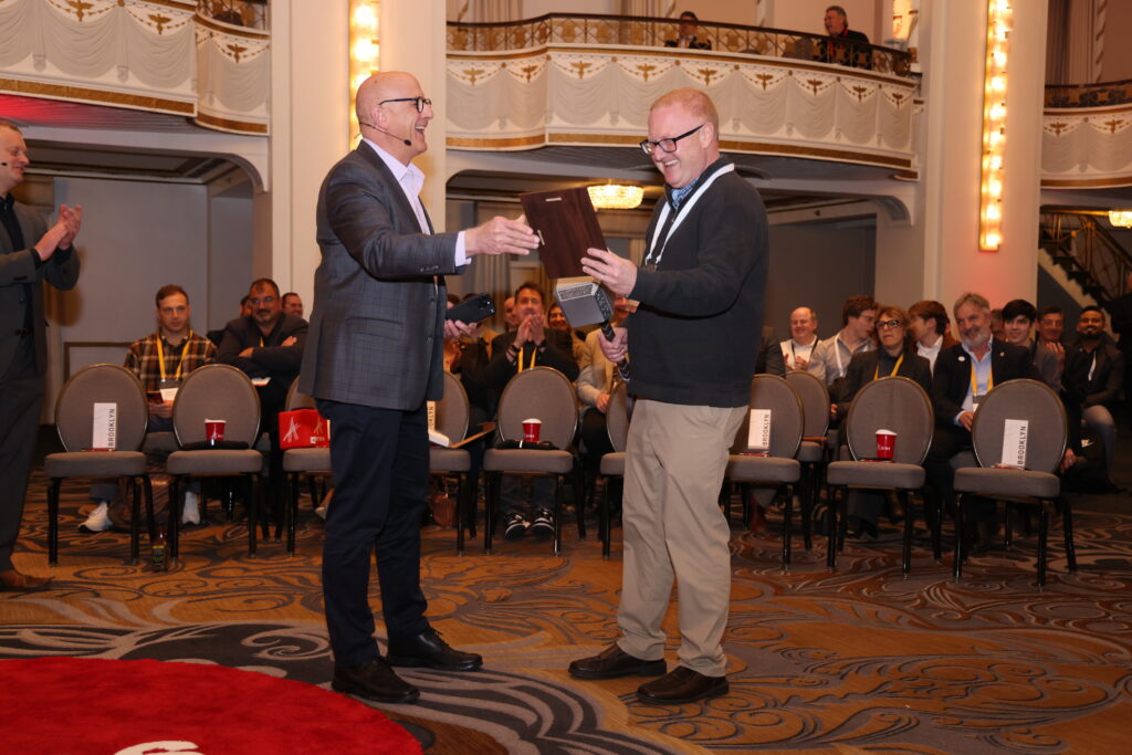 Tom Smith from SMC receives a plaque from Roque Martin for winning the ACE 2025 Innovation Challenge
